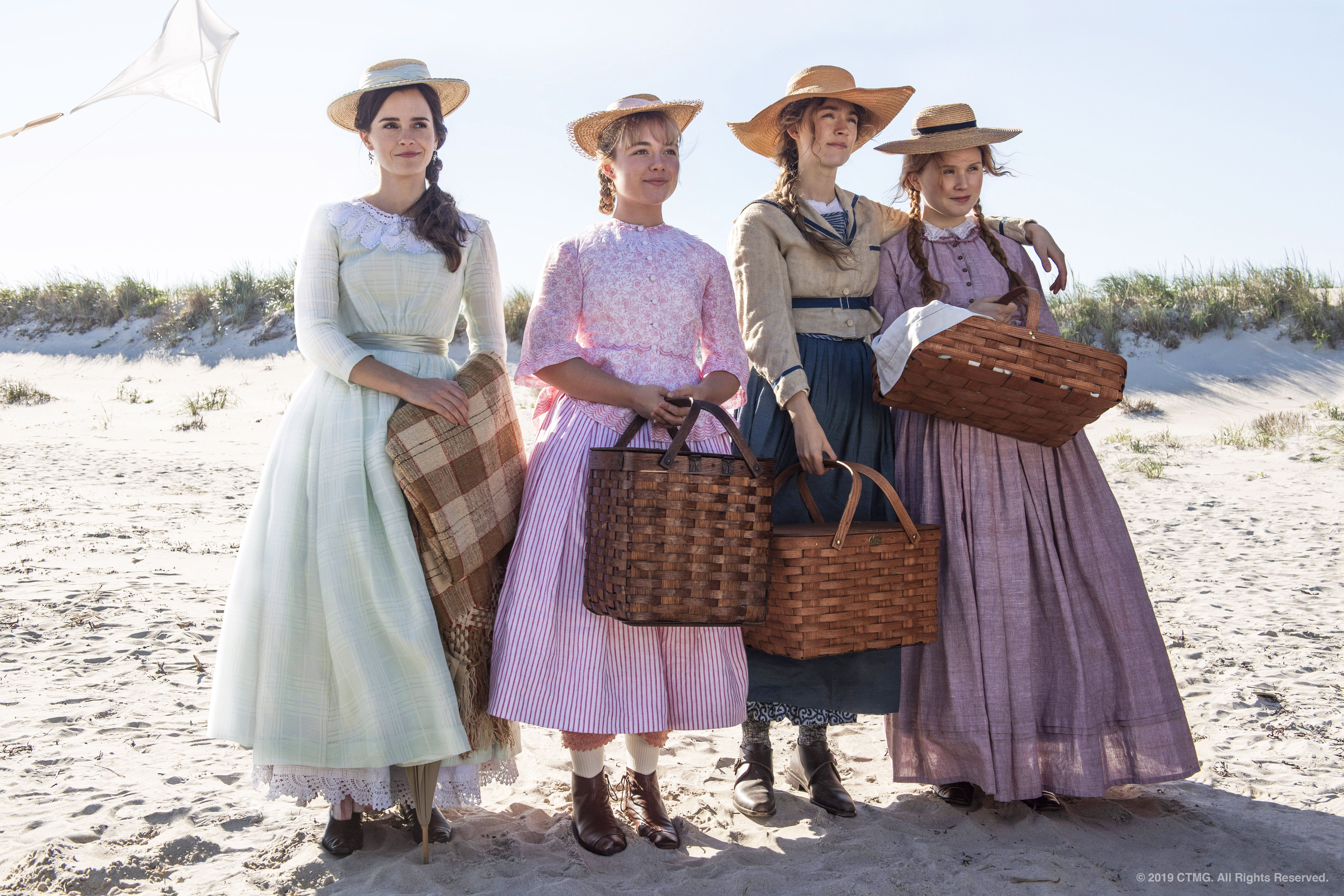 Four women in period costume stand on a beach in a scene from 'Little Women.'