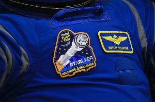 Boeing Starliner Crew Flight Test (CFT) commander Barry "Butch" Wilmore wears the new mission patch for his and Suni Williams' 2023 launch to the International Space Station.