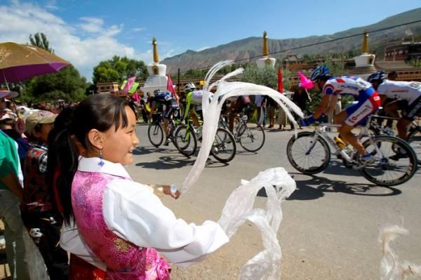 Tibetan girls cheer on the peloton as they pass a monastery.