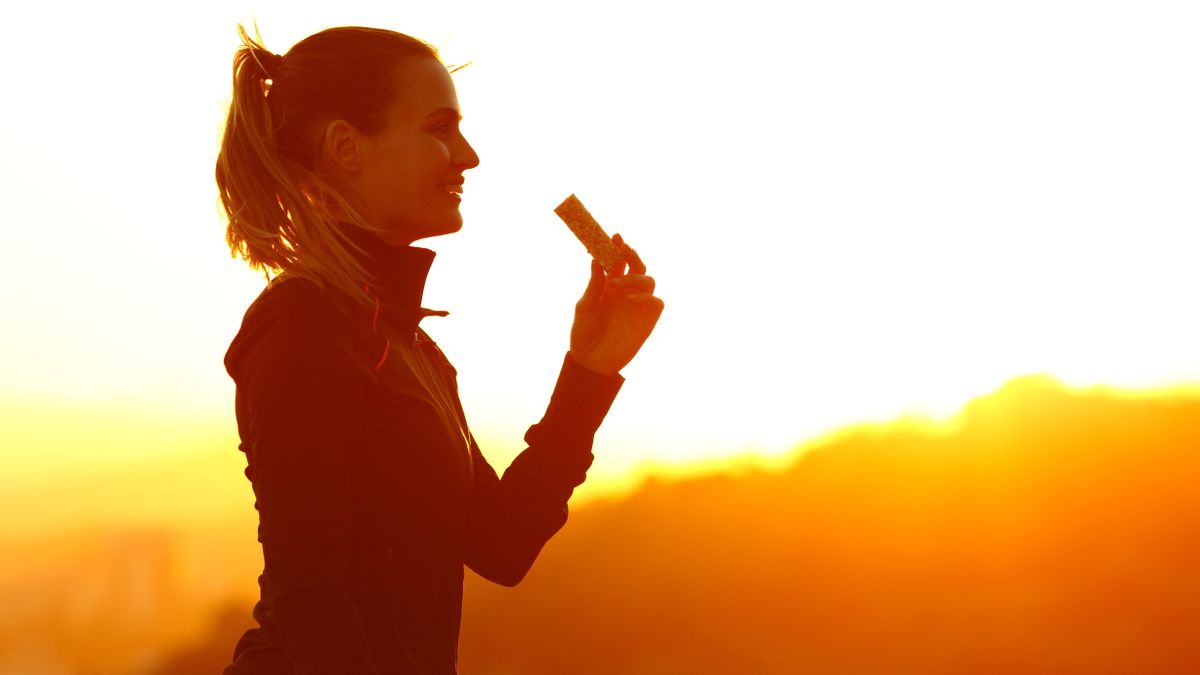 Silhouette of runner eating energy bar after running