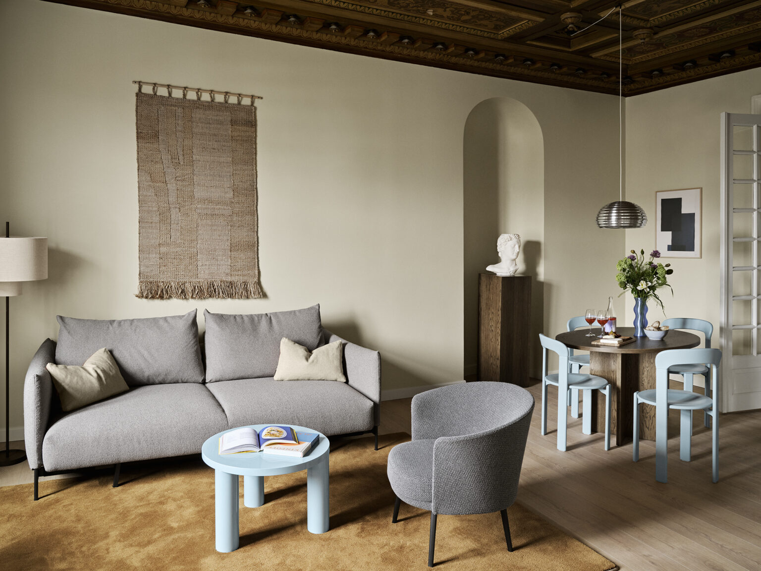 A quirkily furnished Danish apartment mixes colorful accents, like a pale blue coffee tables and chairs, with earthy furnishings that elevate the space through bold sculptural design.