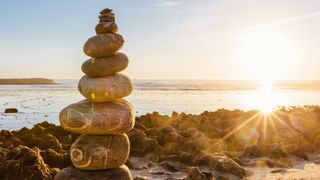 Stones stacked on a beach with sunset in the background
