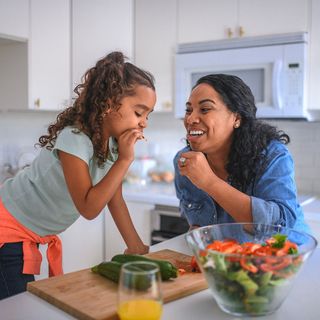 mom and girl eat salad in kitchen