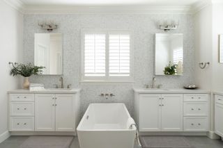 bathroom with freestanding bath and white mosaic tiles and twin vanity units with mirrors above