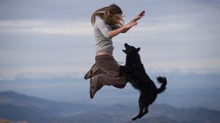 Girl and dog jumping outside