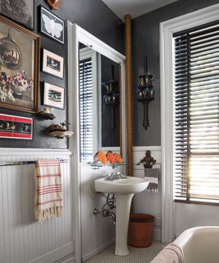 bathroom with dark gray wall with gallery pictures, white trim and white fixtures