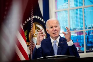 US president Joe Biden speaking to press at the White House while sat in front of the US flag