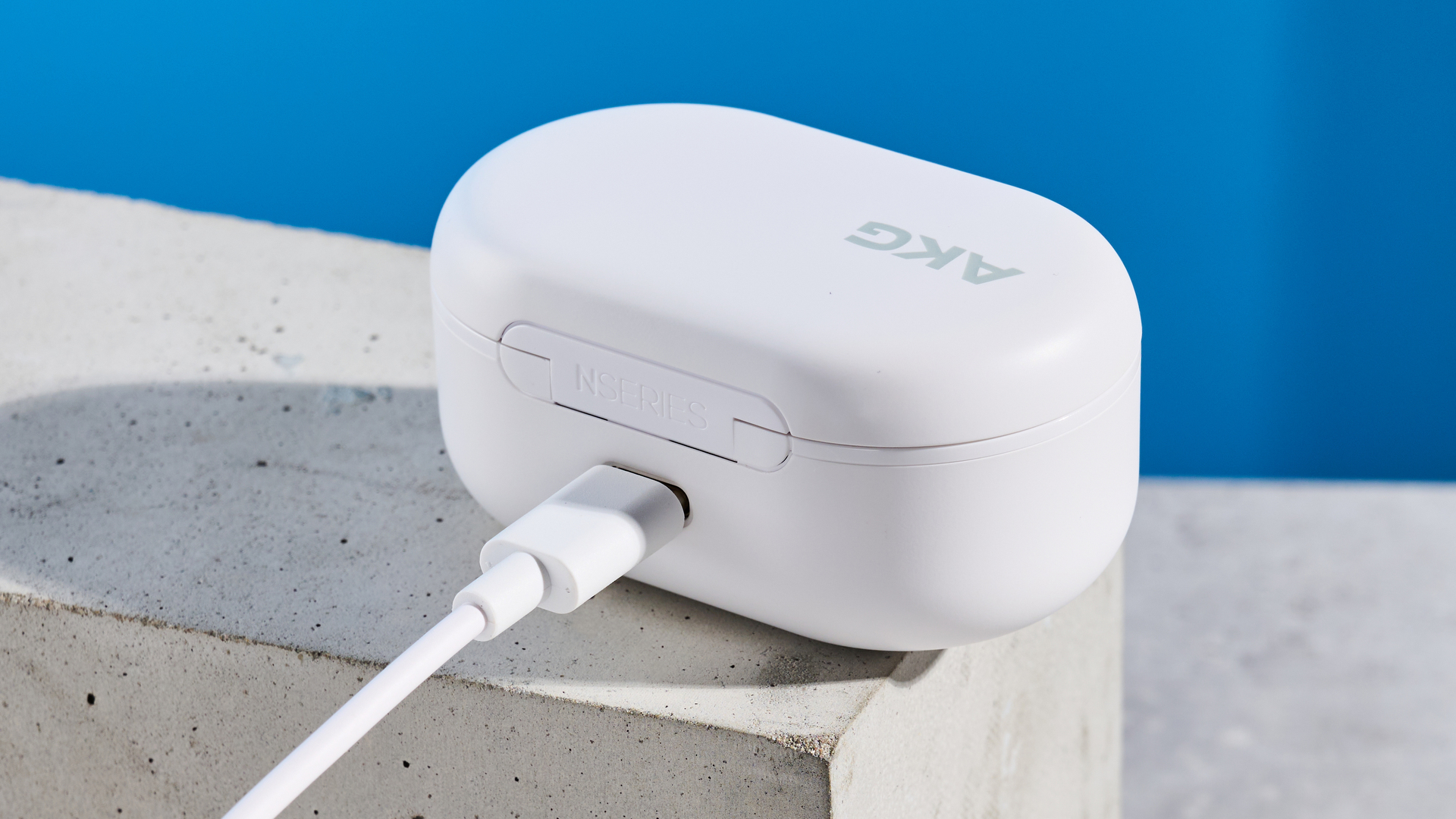 the akg n5 hybrid earbuds by harman in white, shown in their charging case with accessories and without