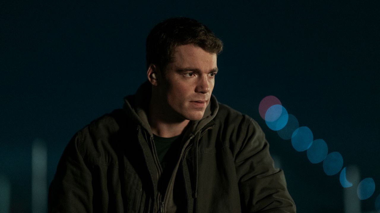 gabriel basso as peter sutherland wearing a jacket outside at nighttime in a still from the night agent season 2