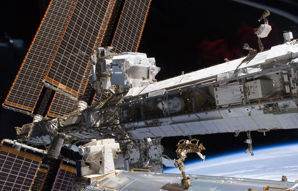 On Flight Day #5 the newly-installed Alpha Magnetic Spectrometer-2 (AMS) is visible at center left. The blackness of space and Earth&#039;s horizon provide the backdrop for the scene.