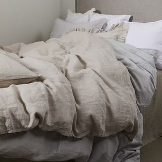 A cream Linen Duvet Set on a crumpled bed