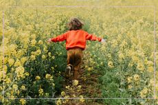 independent child running through a field of flowers 
