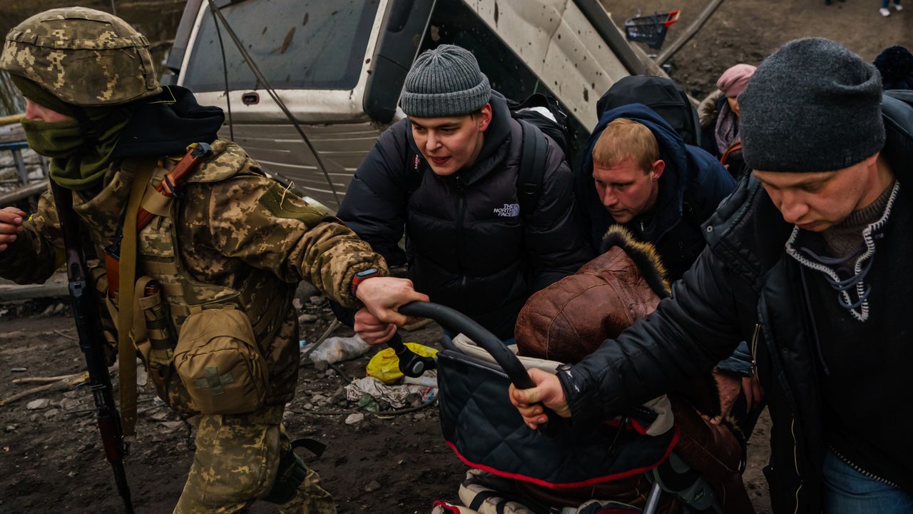 A Ukrainian soldier helps with the evacuation of a child in Irpin, Ukraine