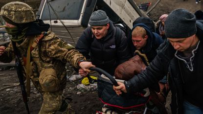 A Ukrainian soldier helps with the evacuation of a child in Irpin, Ukraine