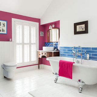 bathroom with white wall and pink towel and wooden floor and bathtub