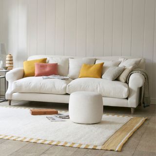 A white sofa covered in different coloured cushions