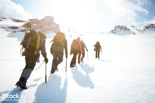 Team hiking up a snowy mountain, from iStock
