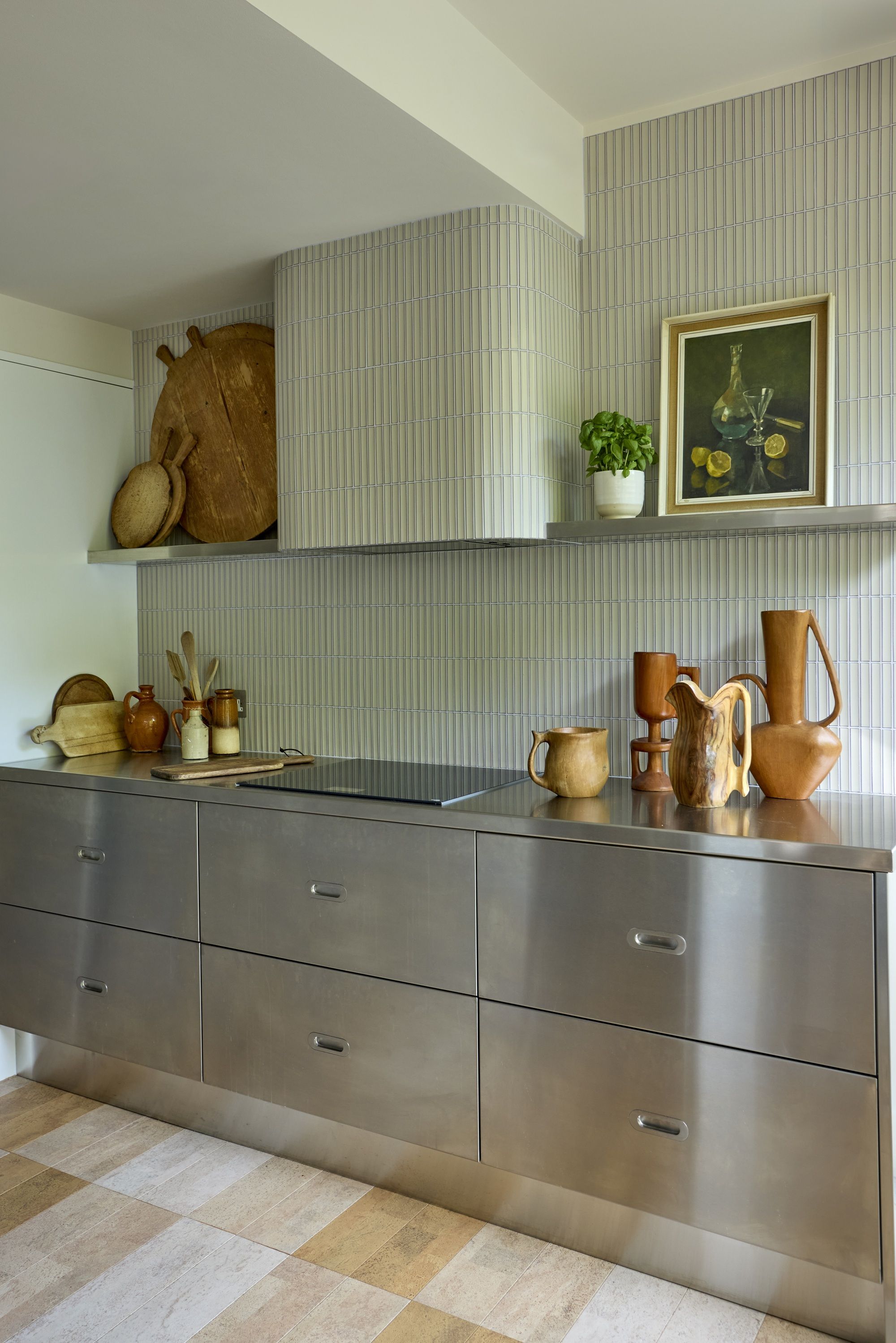 a stainless steel kitchen with a textured tile backdrop dressed with interesting wooden vases and sculptures