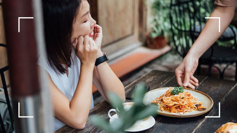 Woman at an outdoor table in a restaurant about to eat a plate of noodles after learning how often should you take a break from keto