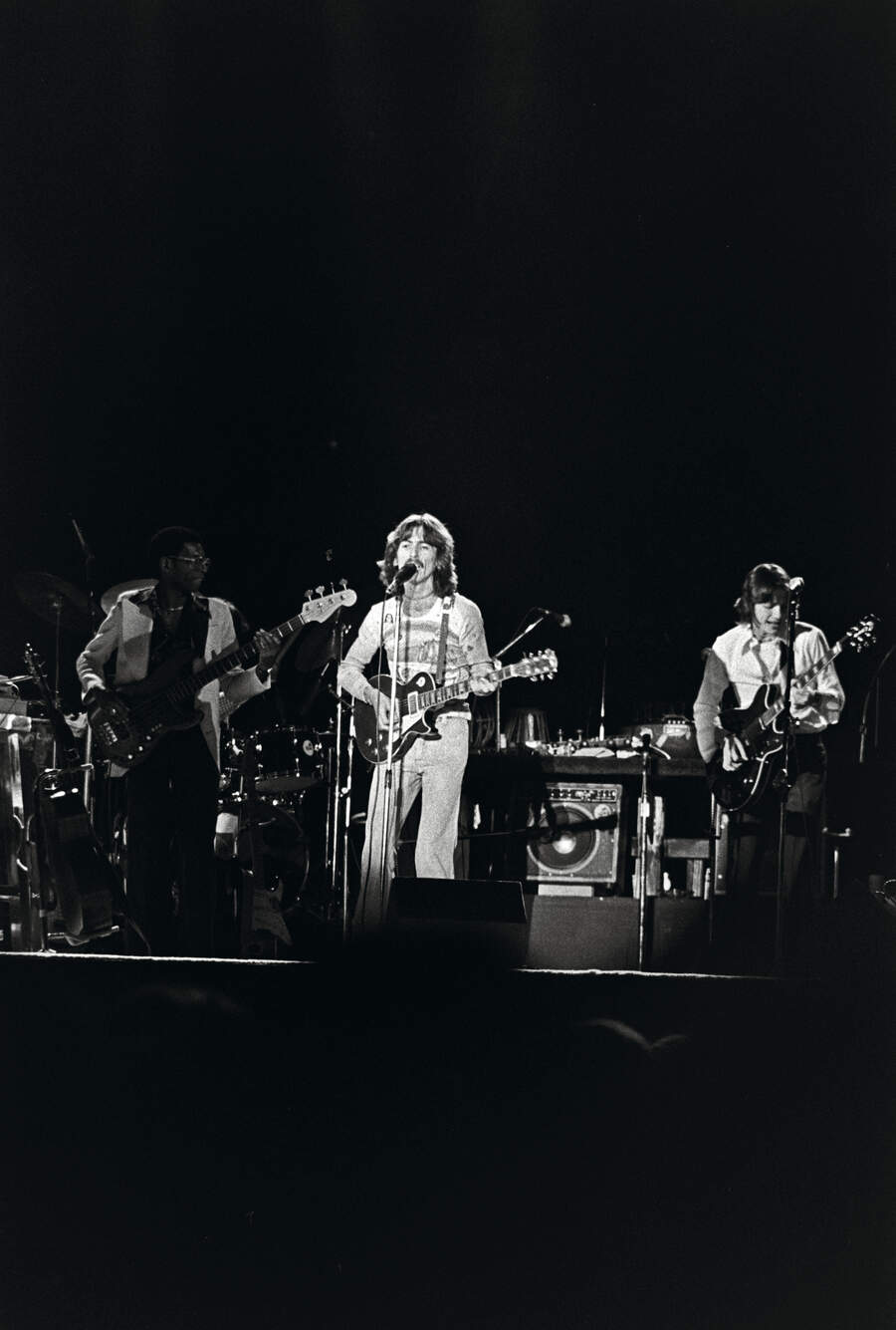 Willie Weeks, George Harrison, and Robben Ford perform onstage at the Forum in Los Angeles in November 1974.