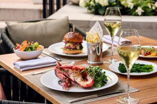 Grilled lobster and salad, a burger and fries and glasses of champagne - presumably Dom Perginon - are on the table at the On The Terrace restaurant