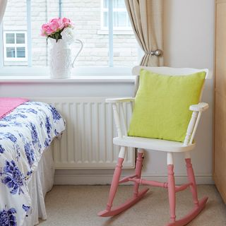 white chair with pink legs and yellow cushion in bedroom near white window