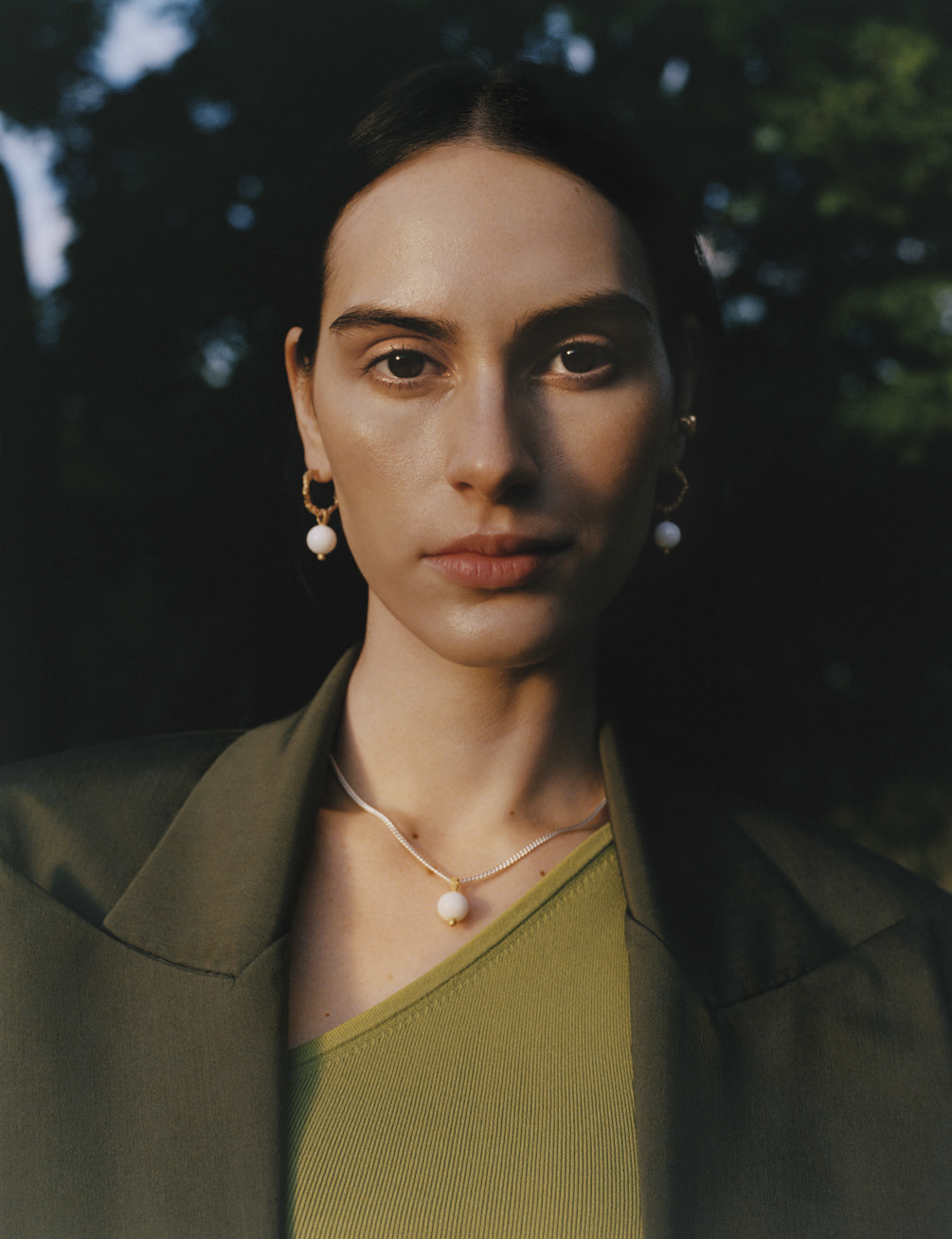 woman wearing necklace and earrings stood outside