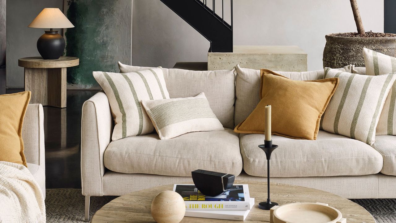 A cream sofa with striped cushions and a stone round coffee table