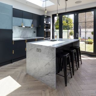 black kitchen with marble surfaces and parquet flooring