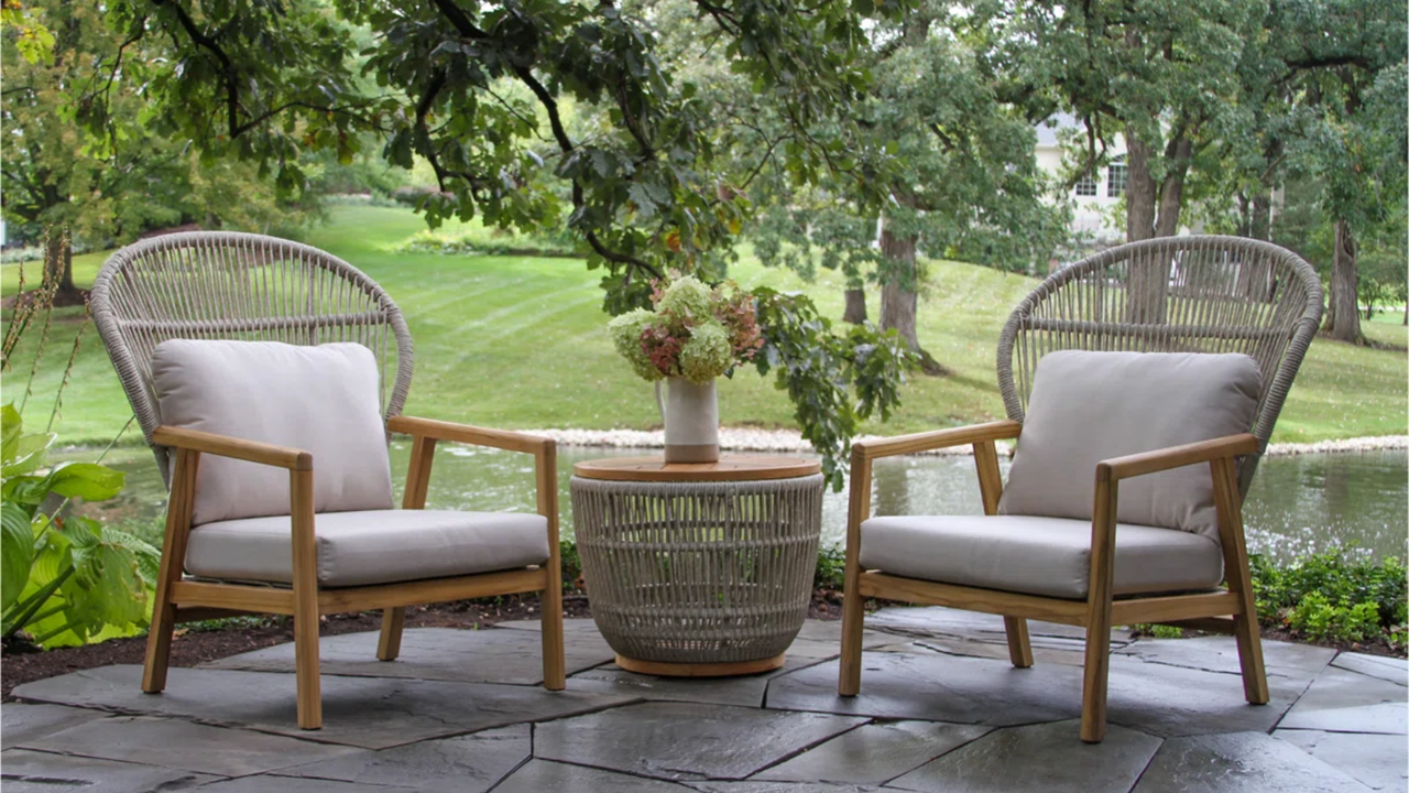 an outdoor seating set up with two chairs, a small table, and a vase of flowers