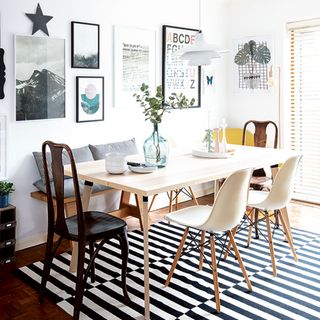 dining room with white gallery wall and monochrome floor rug under the table
