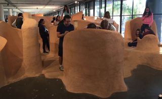 Visitors interact with Rita Ponce de León’s En Forma de nosotros, or ’The Shape of Us,’ 2016, a clay installation sculpted to accommodate the human body.