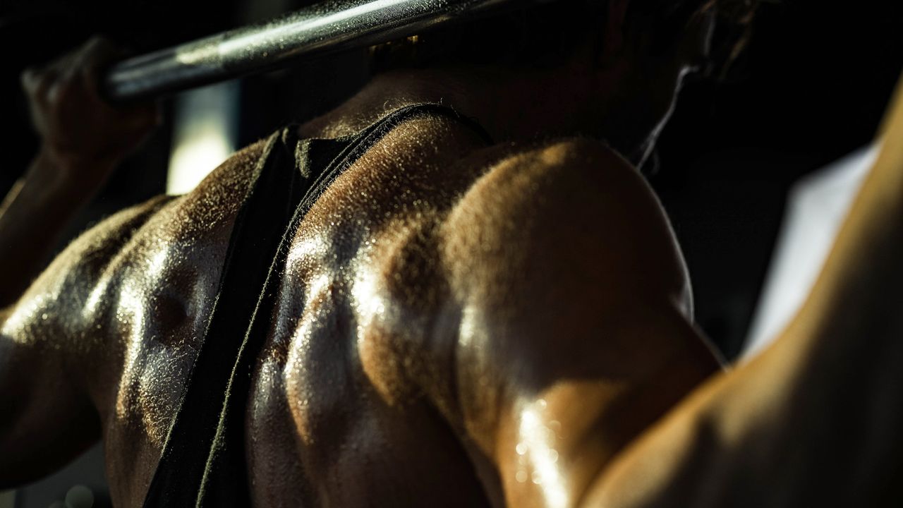 A muscular man with a barbell on his back