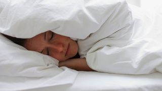 A person with flu sleeping under a duvet