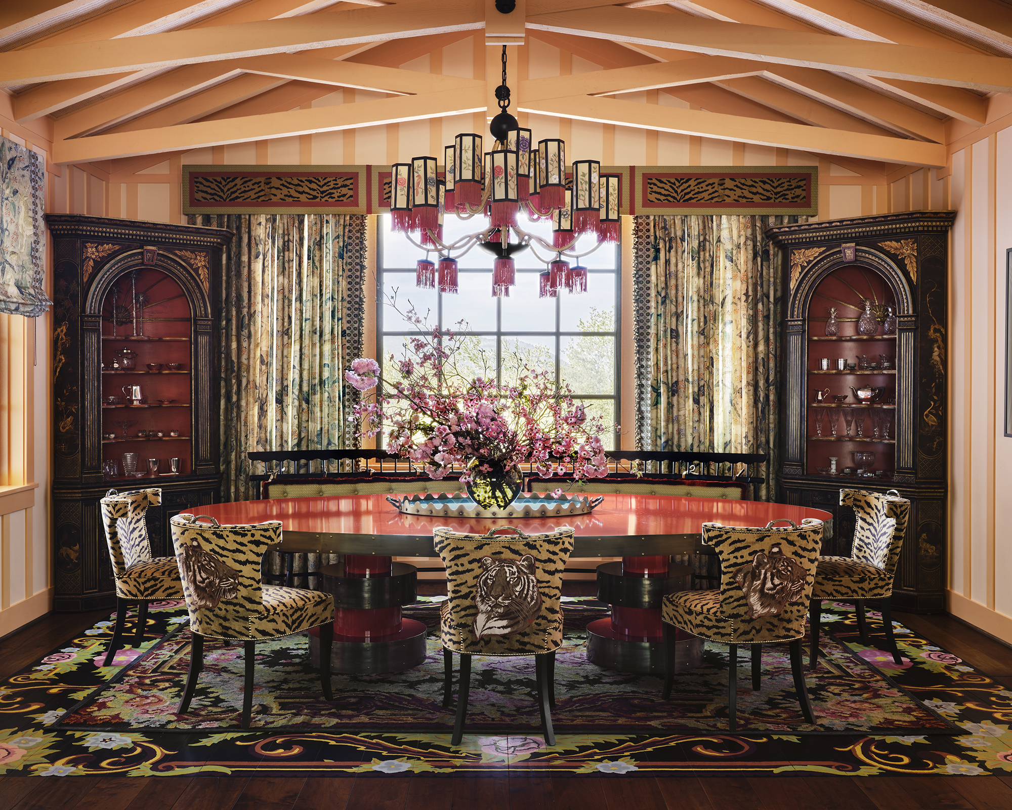 large dining room with leopard print dining chairs and pink chandelier over the table