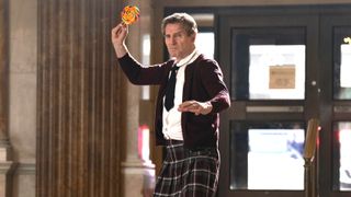 Frank Drebin Jr (Liam Neeson) in a school uniform and preparing to throw a lollipop in a scene from "The Naked Gun" (2025)