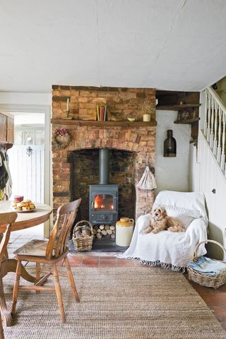 cozy kitchen corner with woodburner lit and dog on white armchair