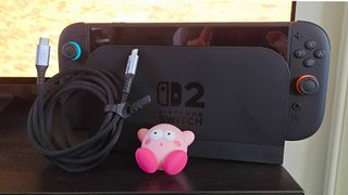 INUI USB-C cable wrapped up next to docked Switch 2 and shocked Kirby figure.