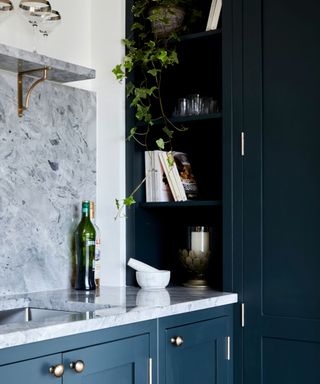 A kitchen corner with white cabinets, blue walls, and dark blue cabinets