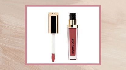 An image of Hourglass Velvet Story Lip Cream in Pure on a beige and pink backdrop