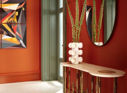 A red entryway with console table, mirror and vase