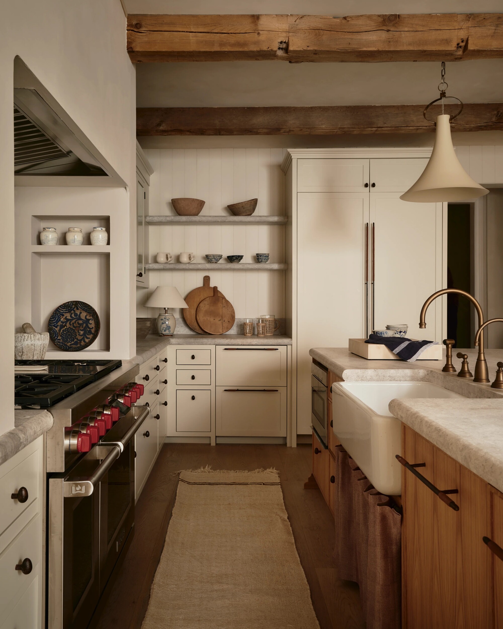 Image of a modern rustic farmhouse style kitchen with off-white walls and cabinetry, light gray marble countertops, and open shelving on the back wall.