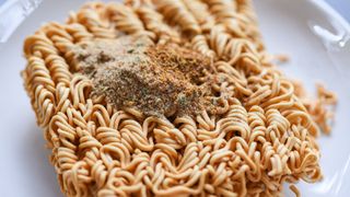 A close-up of dry ramen noodles with powdered seasoning on top