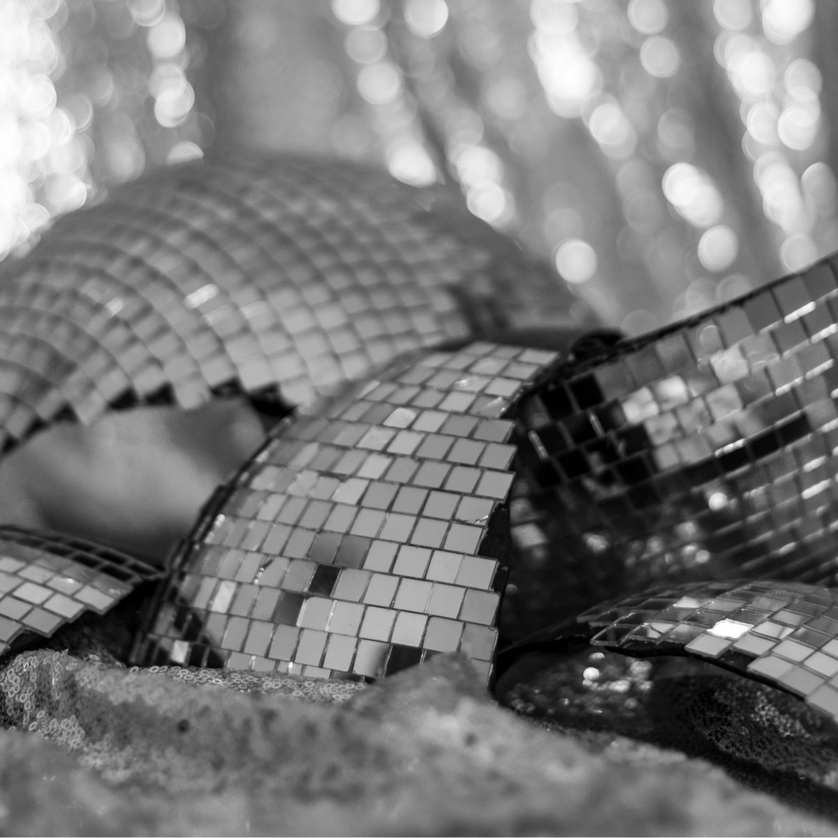 Broken disco ball smashed to pieces on the floor. Black and white for a dramatic touch. Shiny backdrop is defocused.