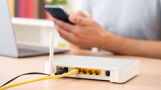 Close up of man hands using multiple devices with broadband router on foreground