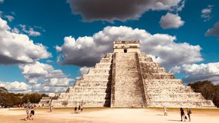 A Maya pyramid in Mexico that includes tourists in the foreground. 