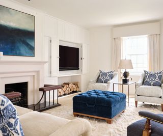 blue and white living room with traditional fireplace and a concealed TV behind cabinetry