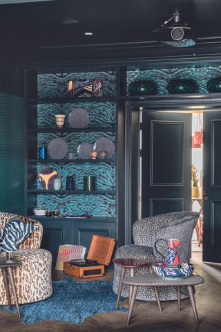 An animal print themed room with black shelving decorated with wallpaper on the shelves