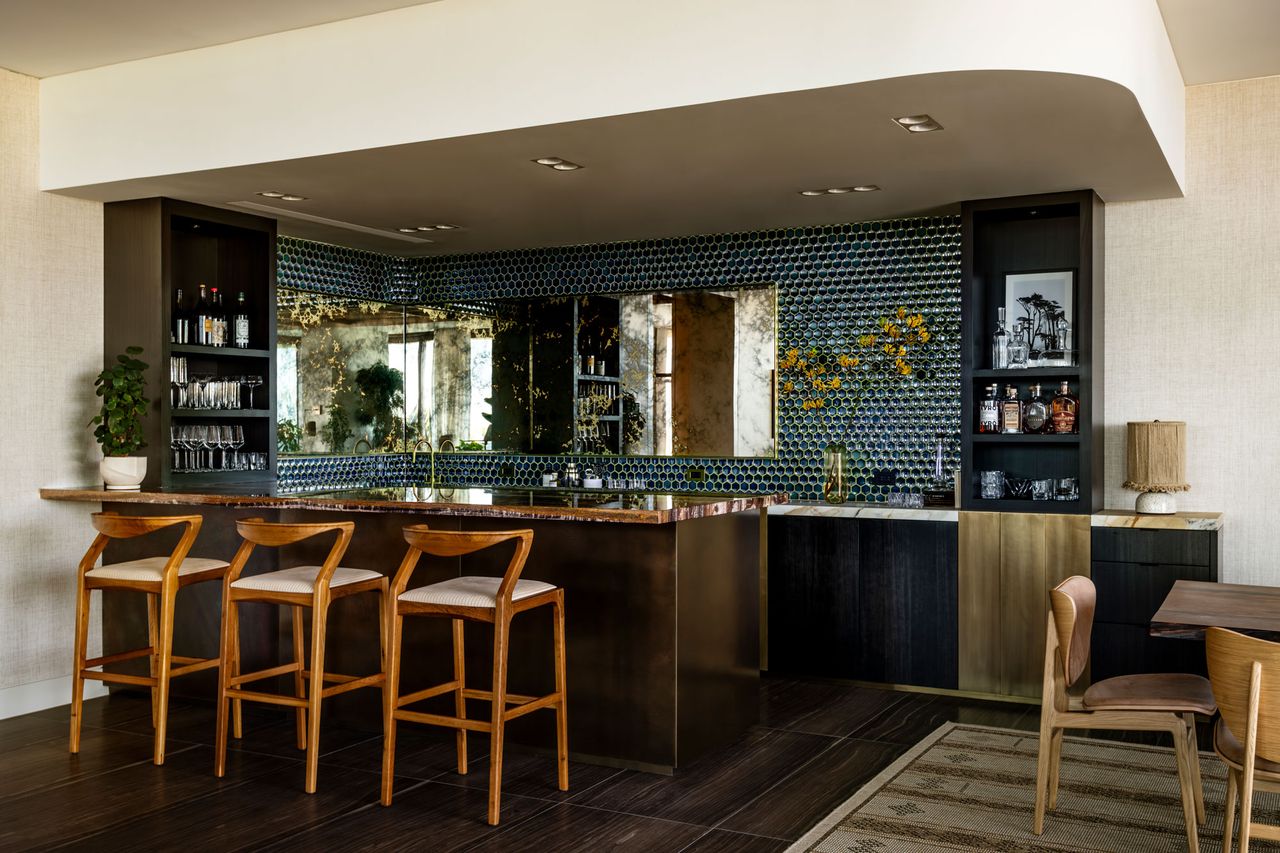 a home bar with a brass finish and blue tile backsplash
