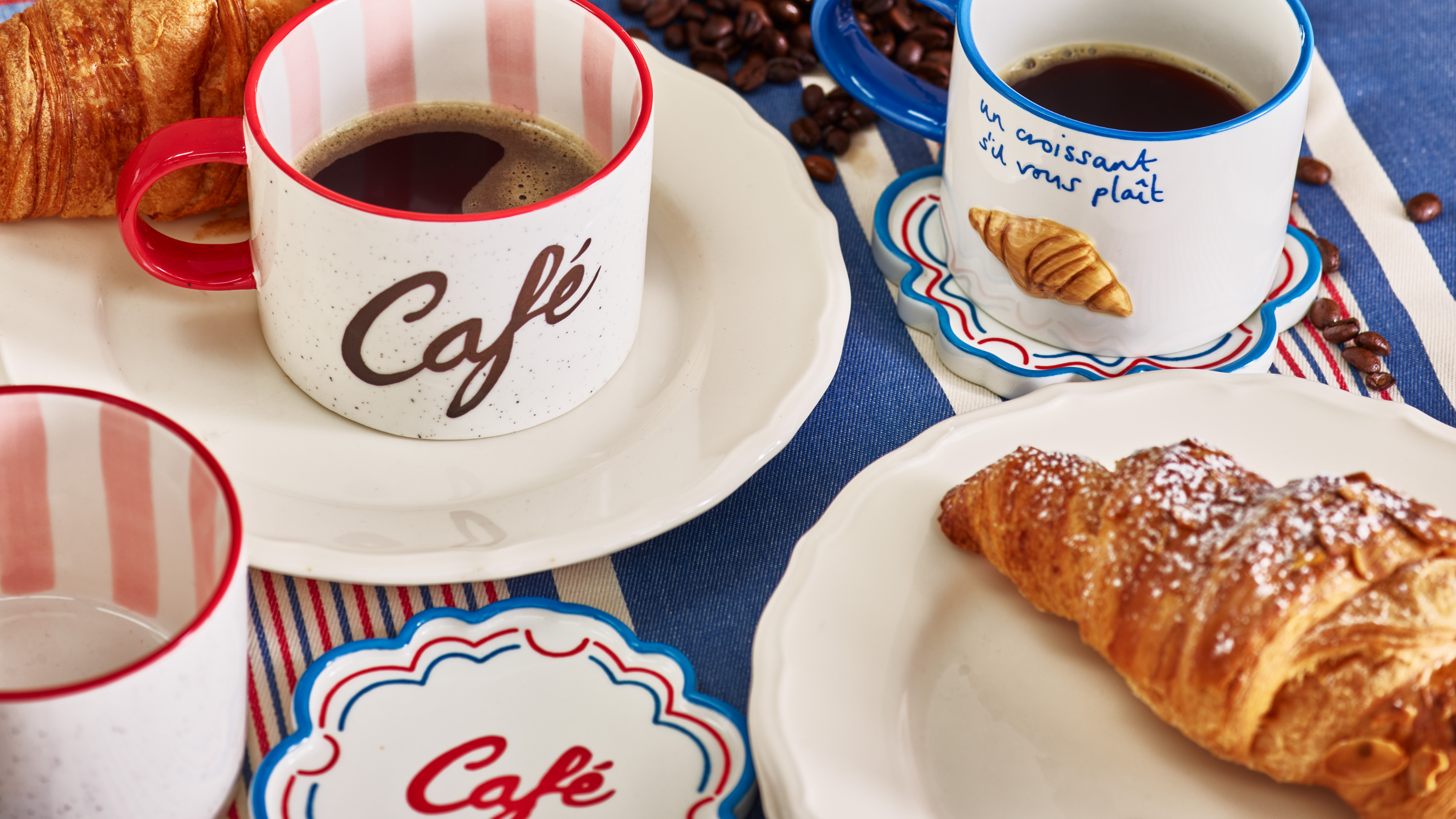 Close-up of striped coffee mugs and croissant.